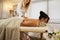 Unrecognizable young masseuse and beautiful young woman on massage table