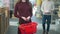 Unrecognizable young slim woman standing in hardware store holding shopping basket as man putting purchases inside and