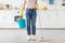 Unrecognizable young woman with bucket of cleaning supplies and mop ready to start wiping kitchen floor, indoors