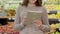 Unrecognizable young woman checking shopping list in tablet and picking kiwi in supermarket. Portrait of serious