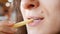 Unrecognizable young woman is eating french fries  in fast food restaurant. She is holding one hand potato, mouth closeup