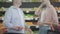 Unrecognizable young woman flirting with man in grocery. Side view of Caucasian brunette stylish lady talking to guy she