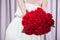 Unrecognizable young woman holding a bouquet of red roses