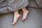 Unrecognizable young woman lying under warm blanke in her bed, close up of feet