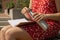 Unrecognizable Young woman in red dress drinking water from metal bottle Writing Gratitude Journal on wooden bench