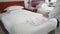 Unrecognized adult senior woman puts and straightens a perfectly white towel next to a white bathrobe on a bed in a