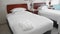 Unrecognized adult senior woman puts and straightens a perfectly white towel next to a white robe on the bed. The