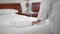 An unrecognized adult senior woman puts a white towel next to a white bathrobe on a bed in a hotel room. Slow Motion