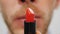 Unrecognized gay man opening red lipstick, close up. Travesty make-up concept