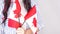 Unrecognized girl student in white blue shirt holding small canadian flag over gray background, Canada day, holiday, vote,