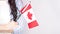 Unrecognized girl student in white blue shirt holding small canadian flag over gray background, Canada day, holiday, vote,