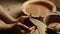 Unrecognized lady creating clay jar in pottery. Closeup woman moistening hands