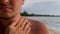 Unrecognized man apply sunblock lotion on body on sea coast background