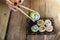Unrecognized woman hand and tasty sushi rolls at wooden table, space for text. Food delivery