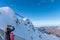 Unrecognized woman taking photo with her phone of a person doing paragliding in the mountain