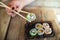 Unrecognized woman and tasty sushi rolls at wooden table, space for text. Food delivery