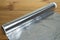 Unrolled roll of aluminum foil for baking on wooden table