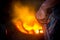 Unsafe worker hands. A local steel machine parts making yard worker melting scrap on hot furnace