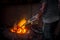 Unsafe worker hands. A local steel machine parts making yard worker melting scrap on hot furnace