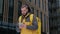 Unshaven caucasian courier in uniform with yellow thermo backpack on his back is looking for delivery address talking on