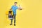 Unshaven caucasian food delivery guy with food from restaurant and yellow thermo bag in his hands holds out food packed