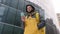 Unshaven courier with yellow backpack on his back in uniform walks down street in winter among tall glass buildings