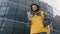 Unshaven courier with yellow backpack on his back in uniform walks down street in winter among tall glass buildings