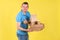 Unshaven young caucasian guy smiling and holding boxes of ready-made food, pizza, coffee, dressed in blue t-shirt and