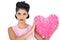 Unsmiling black hair model holding a pink heart shaped pillow