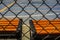 Unstoppable warm color, orange-red bench by the open-air cement basketball court inside the barbed wire