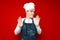 Unsure chef in uniform shrugs hands on red isolated background, kitchen worker in embarrassment