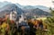 Unsurpassed sunrise in the Alpine mountains. Famous Neuschwanstein Castle in the background of majestic mountains and trees with