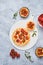 Unsweetened shortbread tartlets with feta cheese, cherry tomatoes and herbs on a white plate on a light concrete background.
