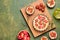 Unsweetened shortbread tartlets with feta cheese, cherry tomatoes and herbs on a wooden board on a green concrete background.