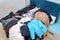 Untidy piles of clothes, arrange on a blue King bed. Women`s suits come in a variety of colors, but men`s pants were a dark tone