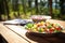 an untouched salad on a sunny picnic table