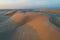 Untouched sand dunes glowing in orange sunrise light.