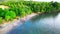 The untouched side of a beach with swashing water and a lo of trees