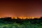 Untreated field with green juicy grass with city on a background in Israel at night.