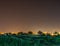 Untreated field with green juicy grass with city on a background in Israel at night.