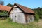 Unused old abandoned dilapidated wooden barn with boarded entrance and cracked boards surrounded with trees and rusted