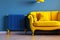 unusual blue heating radiator with temperature controller near yellow sofa