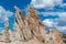 Unusual, craggy rock formations and rugged pinnacles under a beautiful blue sky with white puffy clouds