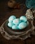 Unusual Easter on dark old background. Ceramic brown bowl with blue eggs. Darkness, rays of sunlight