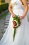 An unusual elongated wedding bouquet in the hands of the bride