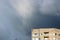 Unusual glow of sunlight through dark gray rain clouds before a thunderstorm in the summer and house.