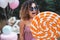 Unusual hipster woman eats a big orange lollypop at her party