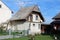 Unusual looking small suburban family house with wooden front porch and tall pointy roof surrounded with large family houses