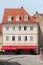 Unusual renovated old apartment building with decorative frames around windows and new roof tiles next to paved road