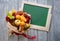 Unusual tasty fruit bouquet. Teacher`s Day. Green school board on a wooden vintage background. Copy space